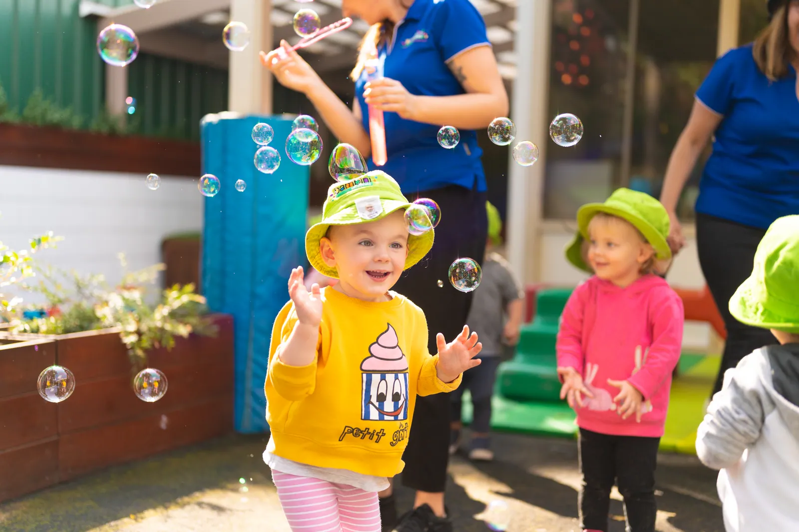 A toddler laughing while catching bubbles outdoors