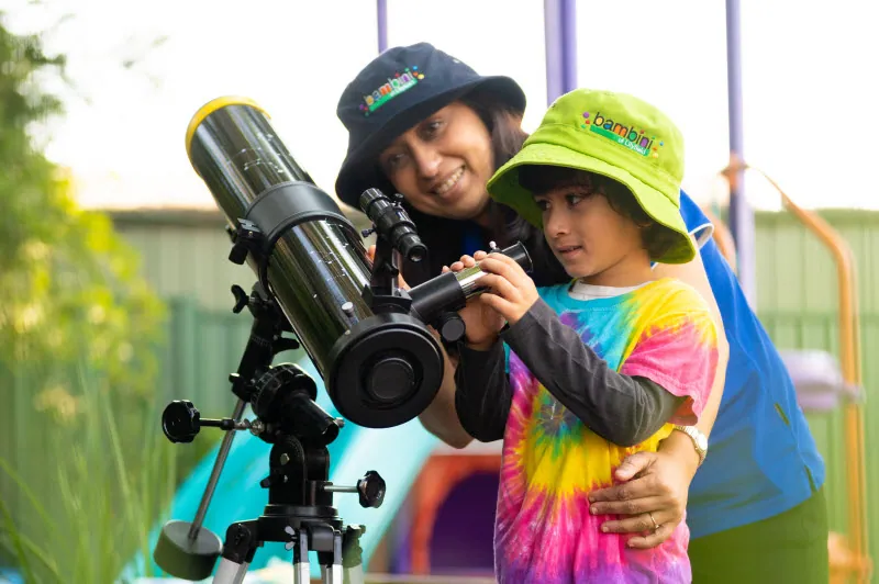 A preschooler looking through a telescope outdoors