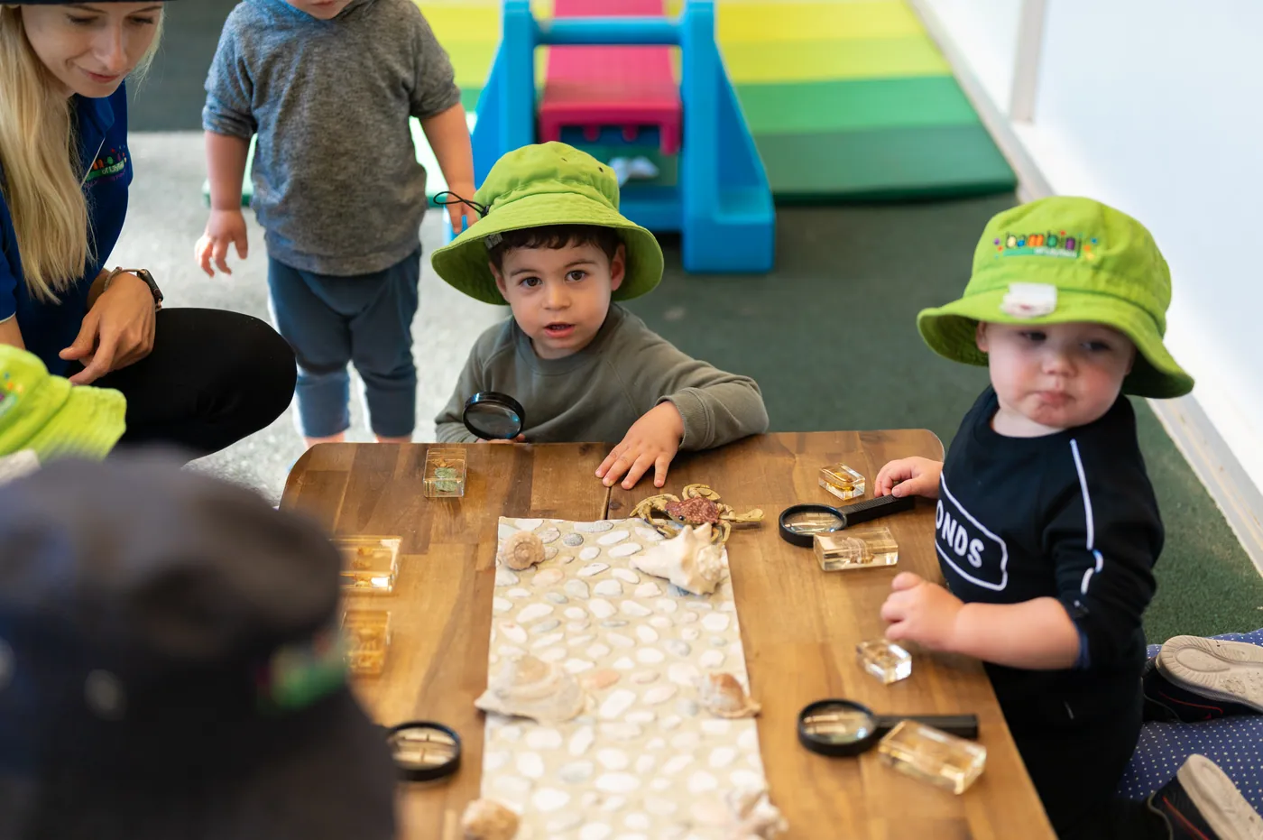 Children at a table investigating objects with magnifying glasses