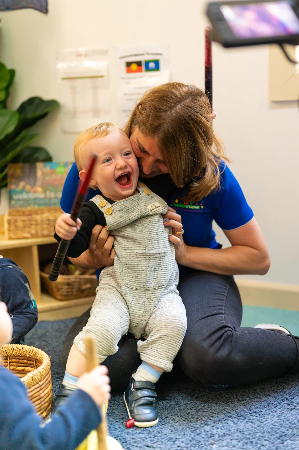 A Bambini educator cheek to cheek with a laughing baby in the Piccolini room
