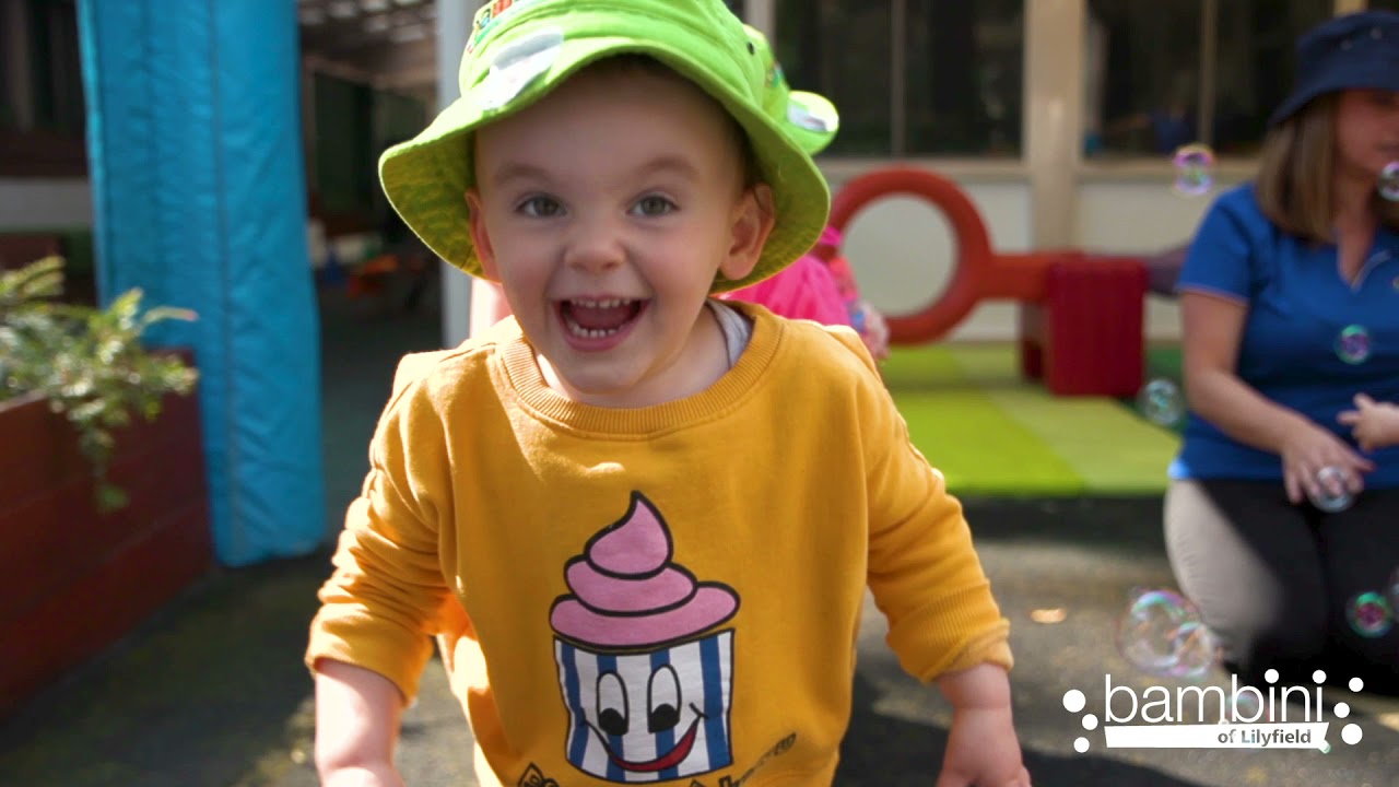 A laughing toddler in a green Bambini hat, from our centre video